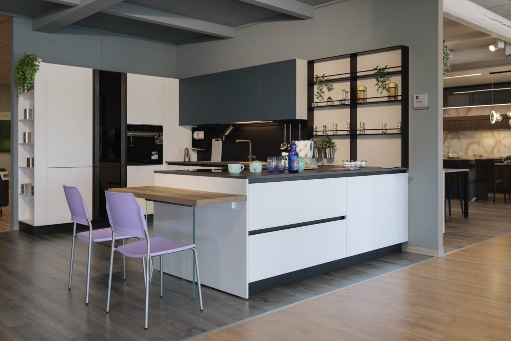 Cucina in esposizione con penisola e tavolino da pasto.